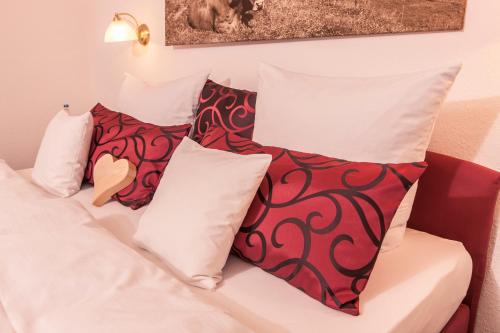 a bed with red and white pillows on it at Hubertushof in Jungholz
