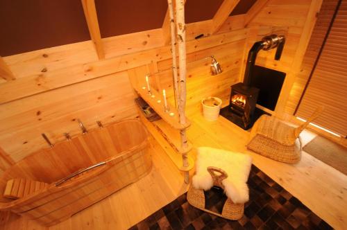 Cabane Lodge Domaine du Lac Chambon في مورول: غرفة مع حوض استحمام وموقد خشبي