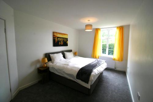 Schlafzimmer mit einem Bett und einem Fenster mit gelben Vorhängen in der Unterkunft Garden House at The Red House Estate in York
