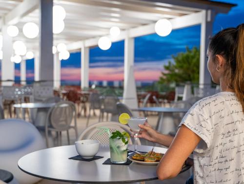 una mujer sentada en una mesa con un plato de comida en Amareclub Red Sun Village, en Isola Rossa