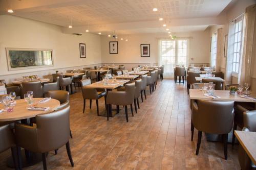 a dining room filled with tables and chairs at Hotel Restaurant Le Bourgneuf in Morlaas