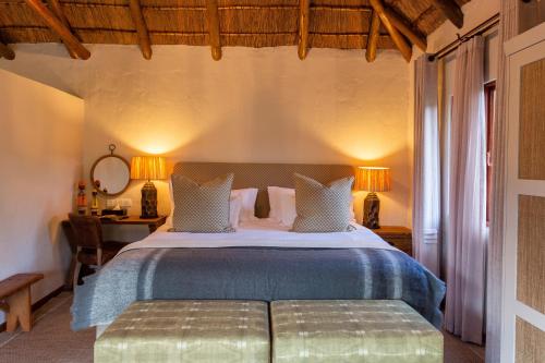 a bedroom with a bed with a table and a desk at Lalibela Game Reserve Mark's Camp in Paterson