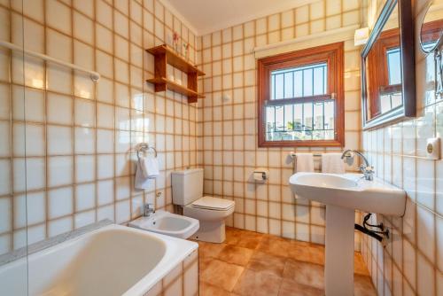 ein Badezimmer mit einer Badewanne, einem WC und einem Waschbecken in der Unterkunft Raiguer in Selva