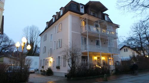 Un grand bâtiment blanc avec balcon se trouve dans une rue. dans l'établissement Villa Bariole, à Bad Reichenhall