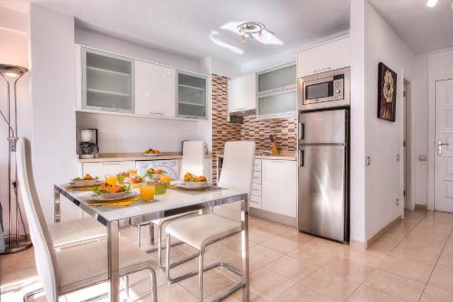a kitchen with a table and a stainless steel refrigerator at Tenerife South Apartments in Playa de las Americas