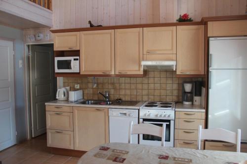 索特的住宿－Tähti A，厨房配有木制橱柜和白色冰箱。