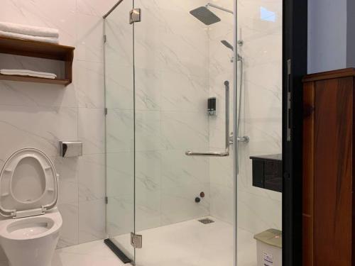 Hào Hoa Hotel Kon Tum في Kon Tum: حمام مع دش زجاجي مع مرحاض
