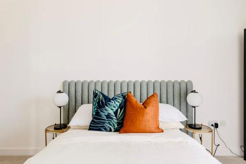 a bed with orange and blue pillows on it at Executive Waterfront Split Penthouse in Woolwich