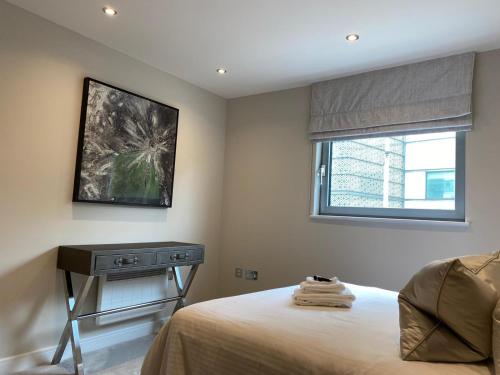 a bedroom with a bed and a table and a window at Exclusive Cardiff City Centre Apartment in Cardiff