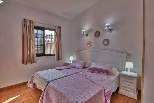 Un dormitorio con una cama con sábanas moradas y una ventana en Bungalow Santa Fe con gran terraza, en Maspalomas