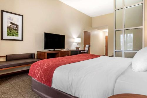 a hotel room with a bed and a flat screen tv at Comfort Suites Vicksburg in Vicksburg