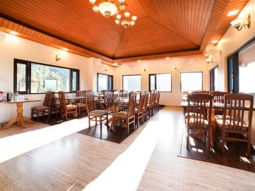 a dining room with tables and chairs and windows at Boros Resorts Binsar in Almora