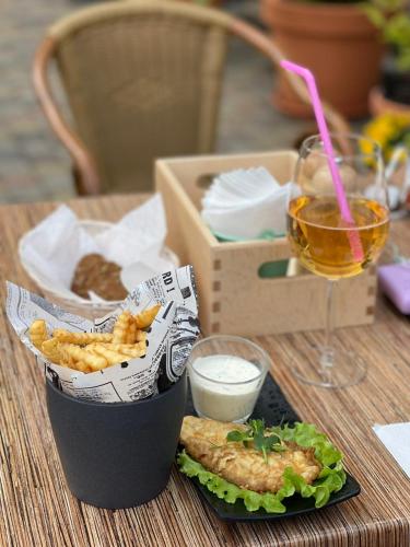 a table with a sandwich and fries and a glass of wine at NB Hotel with Free Parking in Rīga
