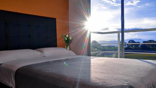 - une chambre avec un grand lit et une grande fenêtre dans l'établissement Apartamento con parqueadero, piscinas y wifi a 5 min del parque del café, à Montenegro