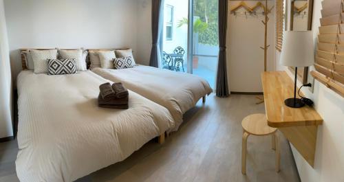 a bedroom with two beds and a table and a desk at Villa Sunbeams ヴィラ・サンビームス in Kin