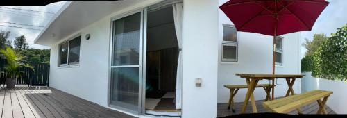 a patio with a table and an umbrella on a house at Villa Sunbeams ヴィラ・サンビームス in Kin