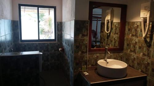 Sunset Beach Hotel في ميريسا: حمام مع حوض ومرآة