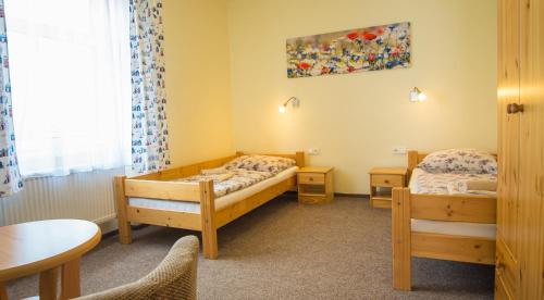 2 Betten in einem Zimmer mit Tisch und Stühlen in der Unterkunft Pension U Koupaliště in Tisá