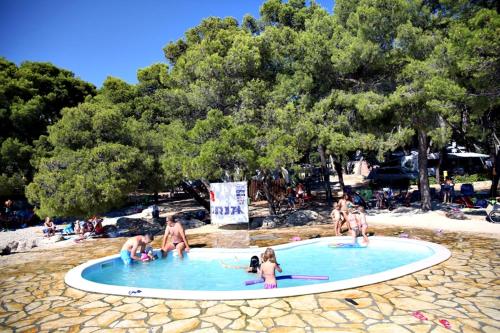 un groupe de personnes dans une piscine sur une plage dans l'établissement Kozarica Apartments, à Pakoštane