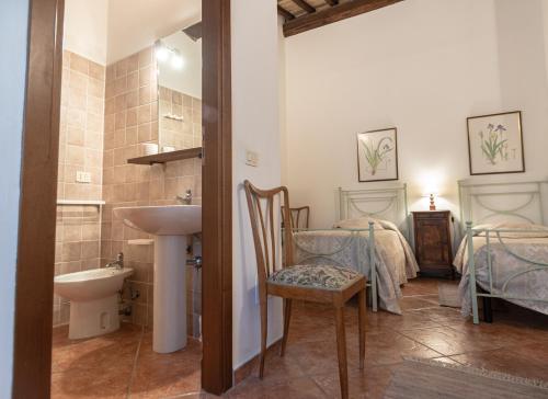 a bathroom with a sink and a toilet and two beds at Agriturismo Sasso Rosso in Capodacqua