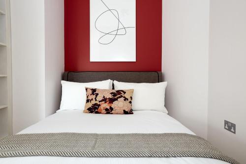 a bedroom with a bed with a red wall at 6VH Virginia House, 31 Bloomsbury Way By City Living London in London