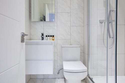 a white bathroom with a toilet and a shower at 6VH Virginia House, 31 Bloomsbury Way By City Living London in London