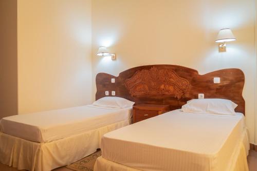 2 bedden in een hotelkamer met witte lakens bij Residencial Cosmos in Assomada
