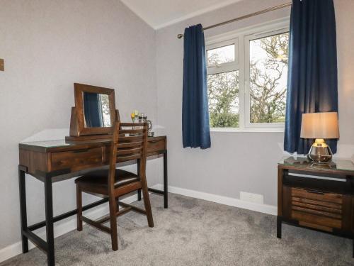 a room with a desk and a mirror and a window at Sycamore Lodge in Helston