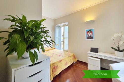 Un dormitorio con una planta en un tocador y una cama en Chic Apartment in San Babila, en Milán