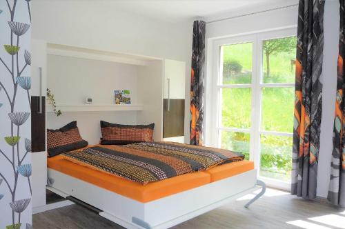 a bedroom with a bed with an orange and black comforter at Ferienwohnung In der Ruhl in Schuttertal
