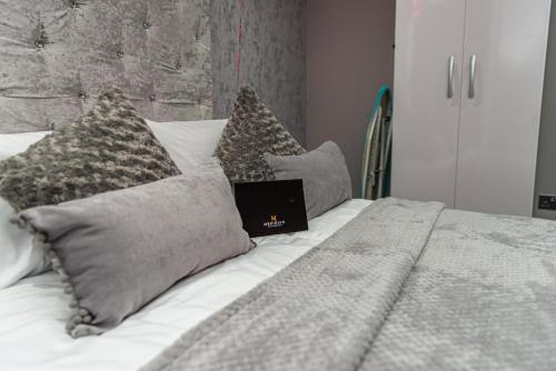 a laptop sitting on top of a bed with pillows at Meridian Serviced Apartments in Bradford