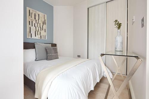 4VH Virginia House, 31 Bloomsbury Way By City Living London في لندن: غرفة نوم بيضاء مع سرير وطاولة زجاجية
