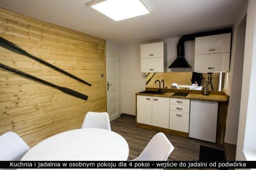 a kitchen with white cabinets and a wooden wall at Ośrodek Wypoczynkowy AKWA Marina in Nysa