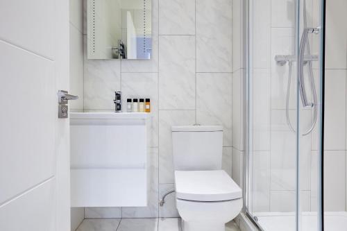 a white bathroom with a toilet and a shower at 4VH Virginia House, 31 Bloomsbury Way By City Living London in London