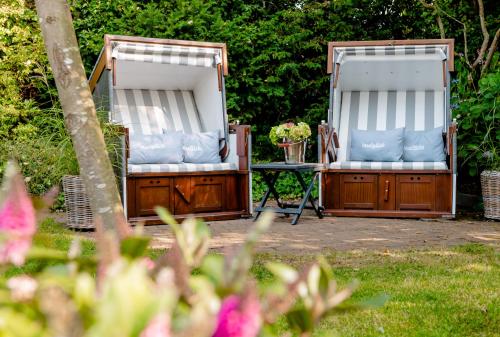 two beds in a yard with a table and flowers at Jaumann's Südwind Sylt in Westerland (Sylt)