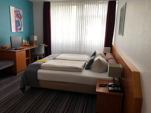 a bedroom with a bed and a desk with a computer at Hotel Servatius in Cologne