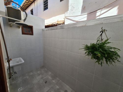 uma casa de banho com uma planta numa parede de azulejos em Vilage novo praia do forte 3 em Mata de São João