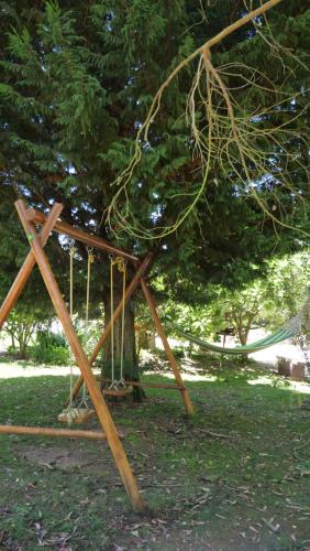 a wooden swing set in front of a tree at Casa Alfazema, Quinta Carmo - Alcobaça - Nazaré in Alcobaça