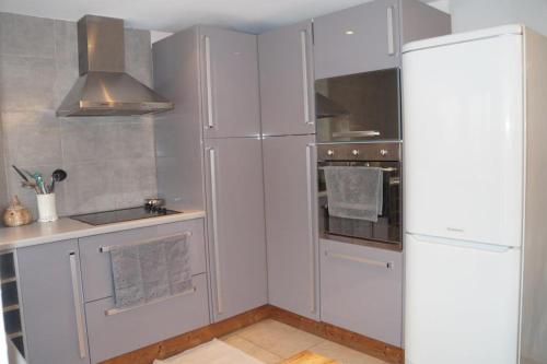 a kitchen with white cabinets and a refrigerator at A l'oree du bois - Gite in Hostun