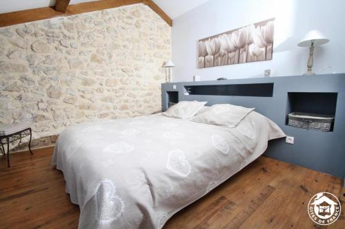 a bedroom with a white bed with a stone wall at A l'oree du bois - Gite in Hostun