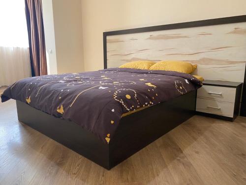 a bed with a purple comforter and yellow pillows at Затишні апартаменти in Chernivtsi