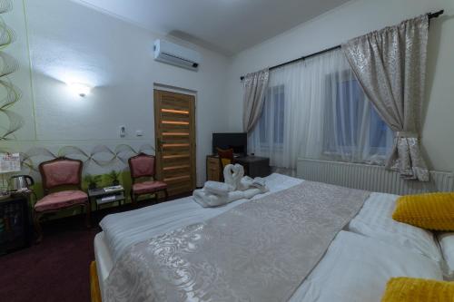 a bedroom with a large white bed with two chairs at Penzión Deloris in Trenčín