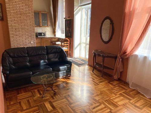 a living room with a leather couch and a glass table at Apartment with city history in the center in Dnipro