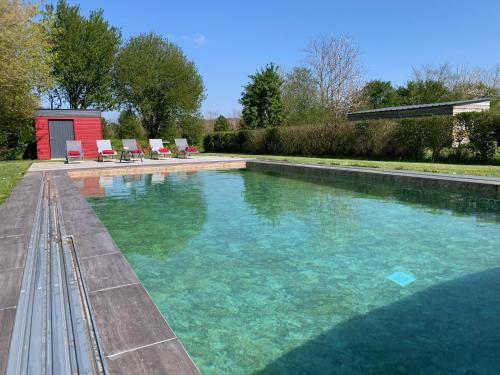 una gran piscina con sillas en un patio en Gîte du Manoir du Cosquer en Pommerit-Jaudy