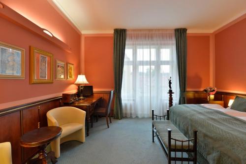 プラハにあるホテル ハスタル プラハ オールド タウンのベッド、デスク、窓が備わるホテルルームです。