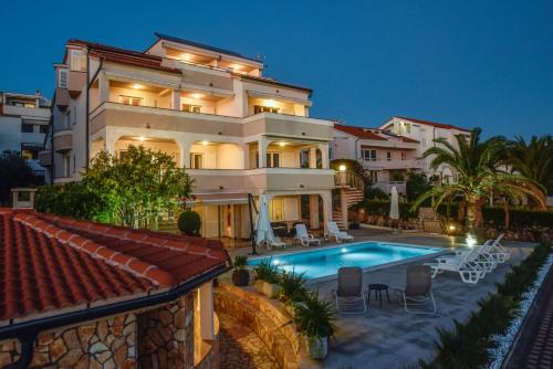 a large building with a swimming pool in front of it at Beachfront Apartments Tolo with Pool in Novalja