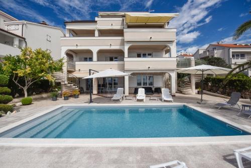 a villa with a swimming pool in front of a house at Beachfront Apartments Tolo with Pool in Novalja
