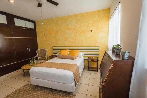 a bedroom with a bed and a desk and a television at Casa Tulita Mérida in Mérida