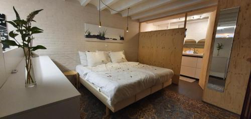 a bedroom with a white bed and a kitchen at Waar Maas & Waal..... in Woudrichem