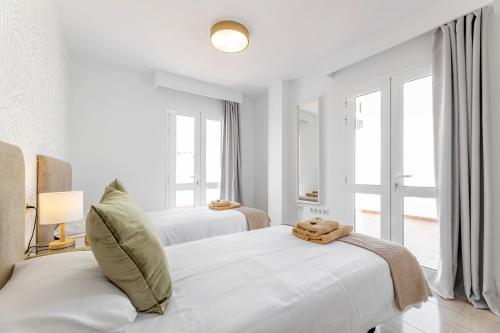 a white bedroom with two beds and two windows at Apartments Urban Arrecife in Arrecife